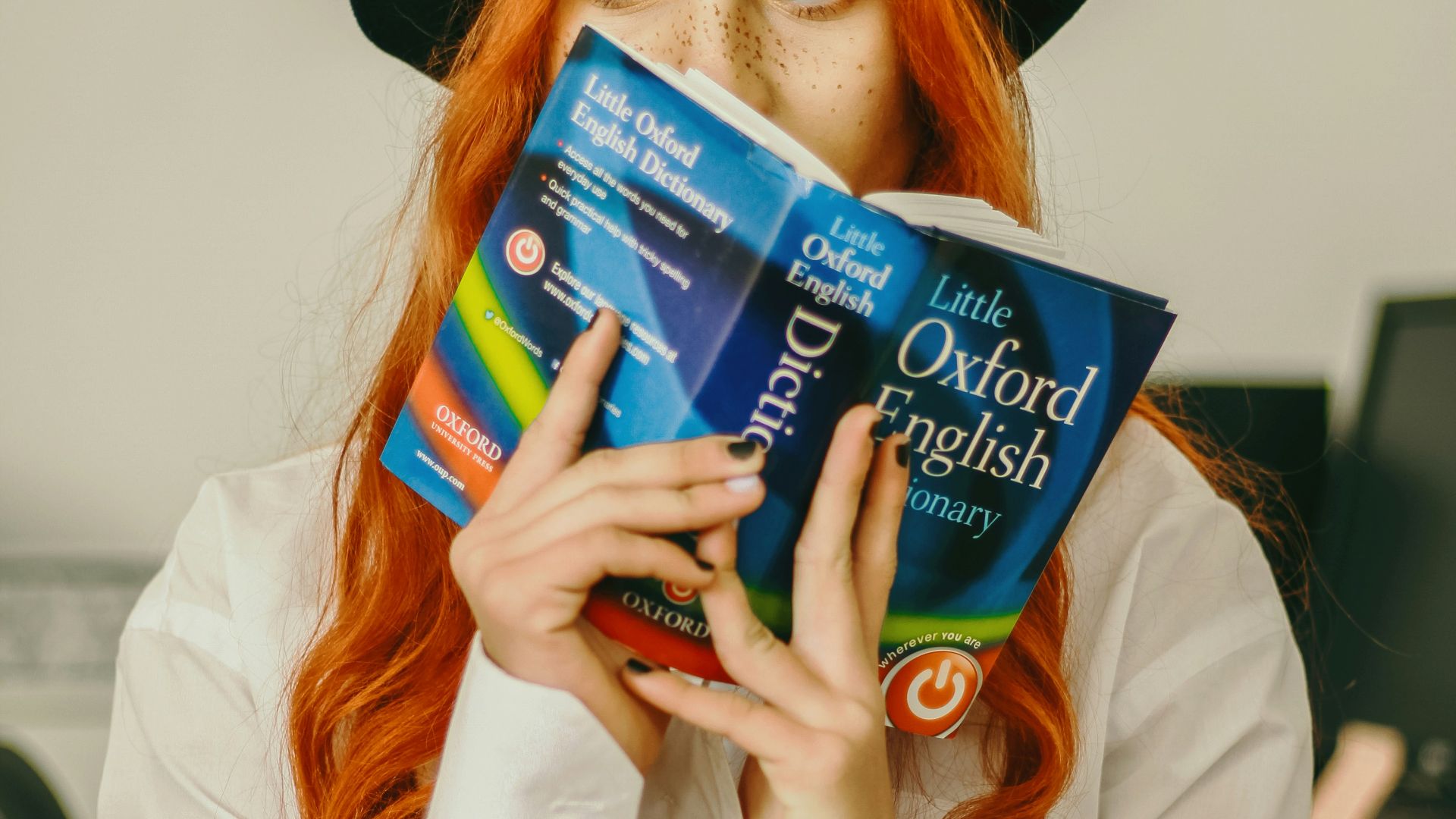 a woman with red hair is holding a book