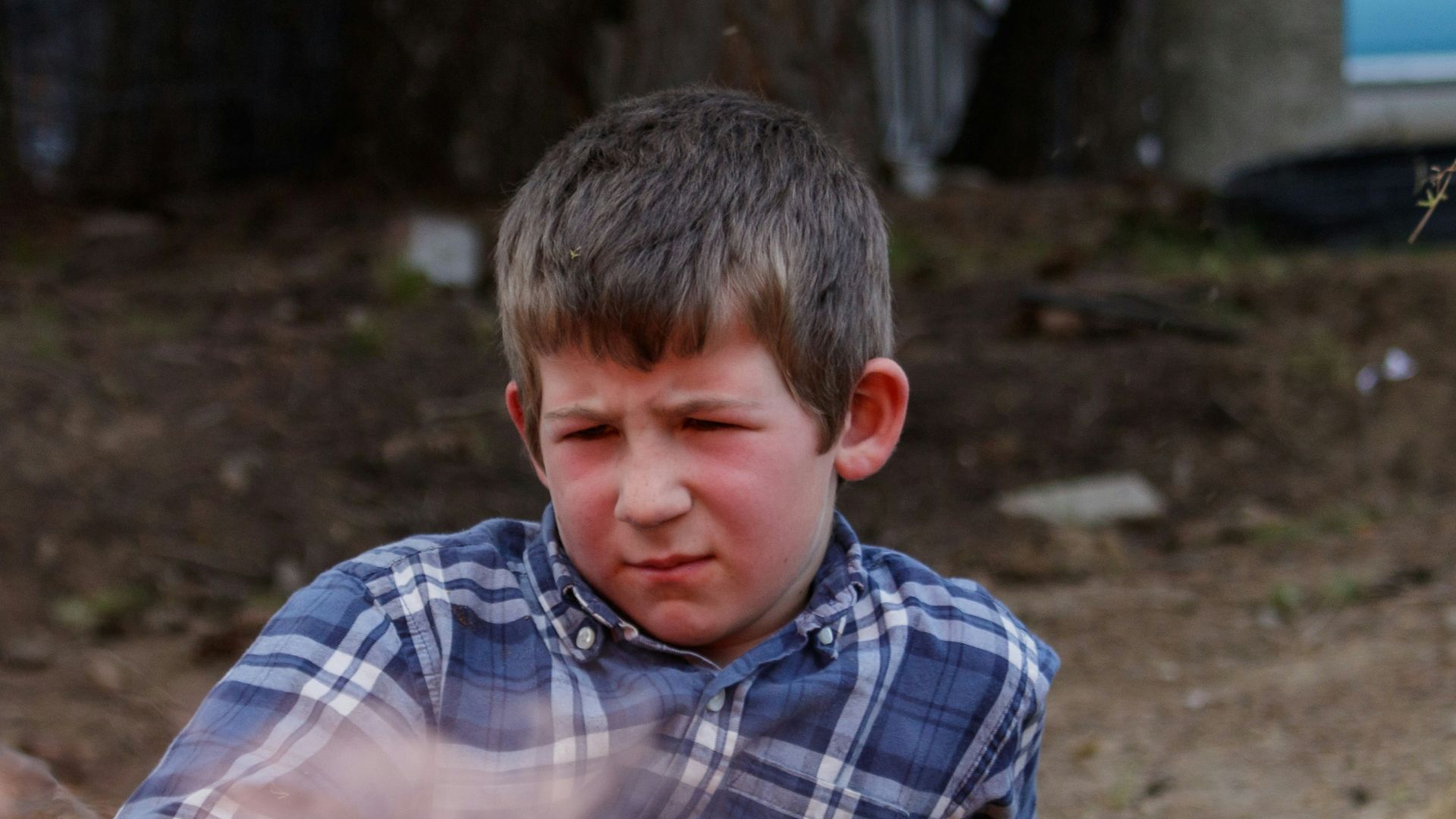 a boy sitting next to a fire