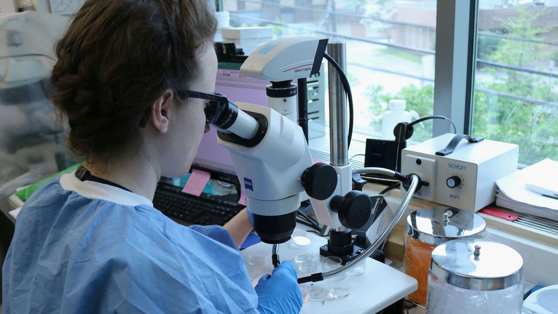 a woman in a lab coat looking through a microscope