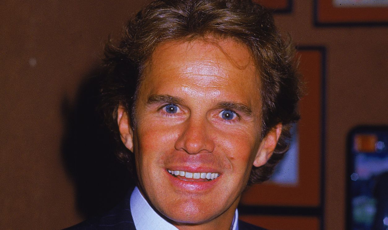  Gettyimages - 53145354, Actor Dack Rambo Portrait of American actor Dack Rambo (1941 - 1994) wearing a blue pinstriped suit and pink tie, smiling at the camera, 1980s.