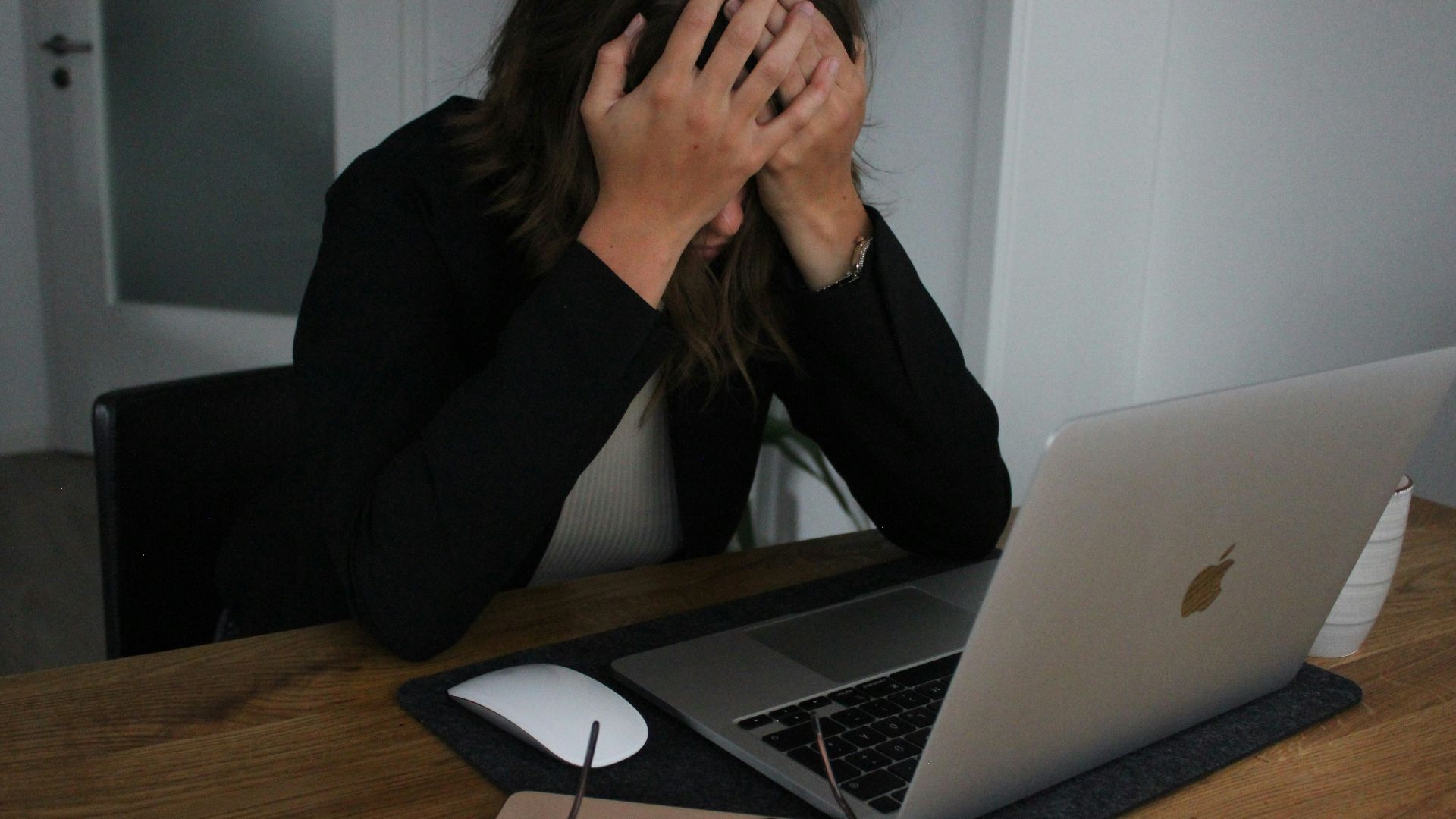 a woman covering her face while looking at a laptop