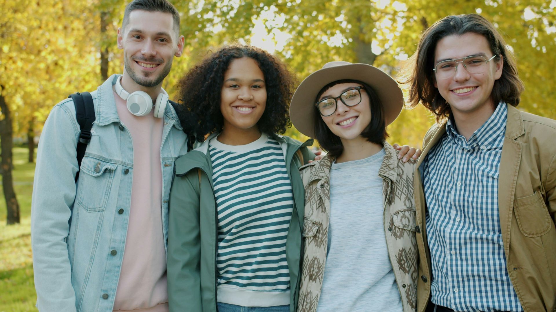 Four friends smiling in a park during autumn