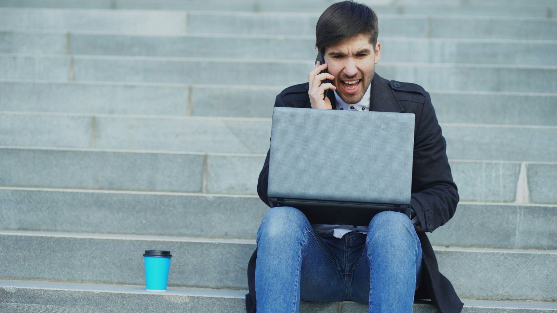 Man on phone with laptop on stairs