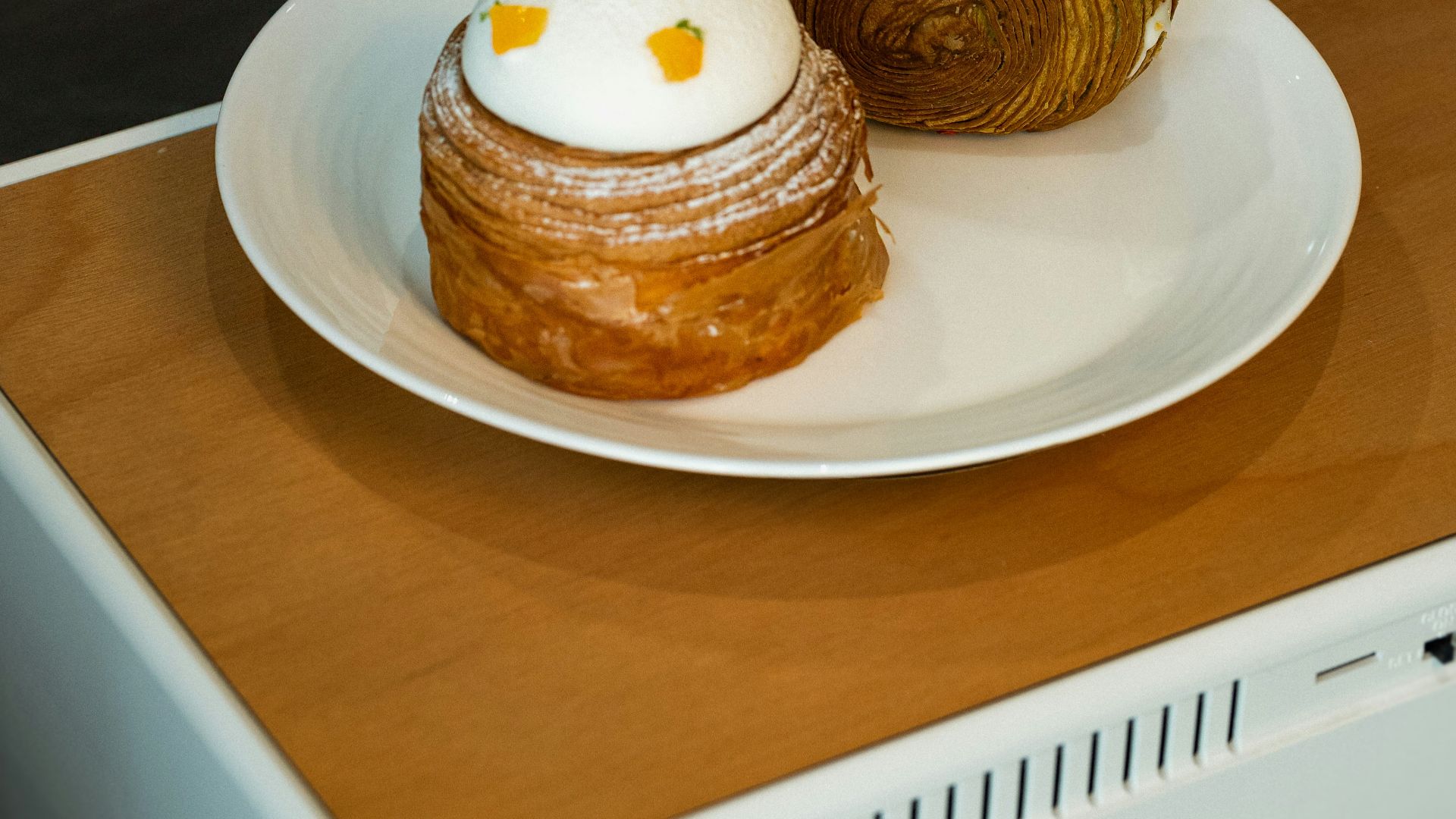 a white plate topped with a pastry on top of a wooden table
