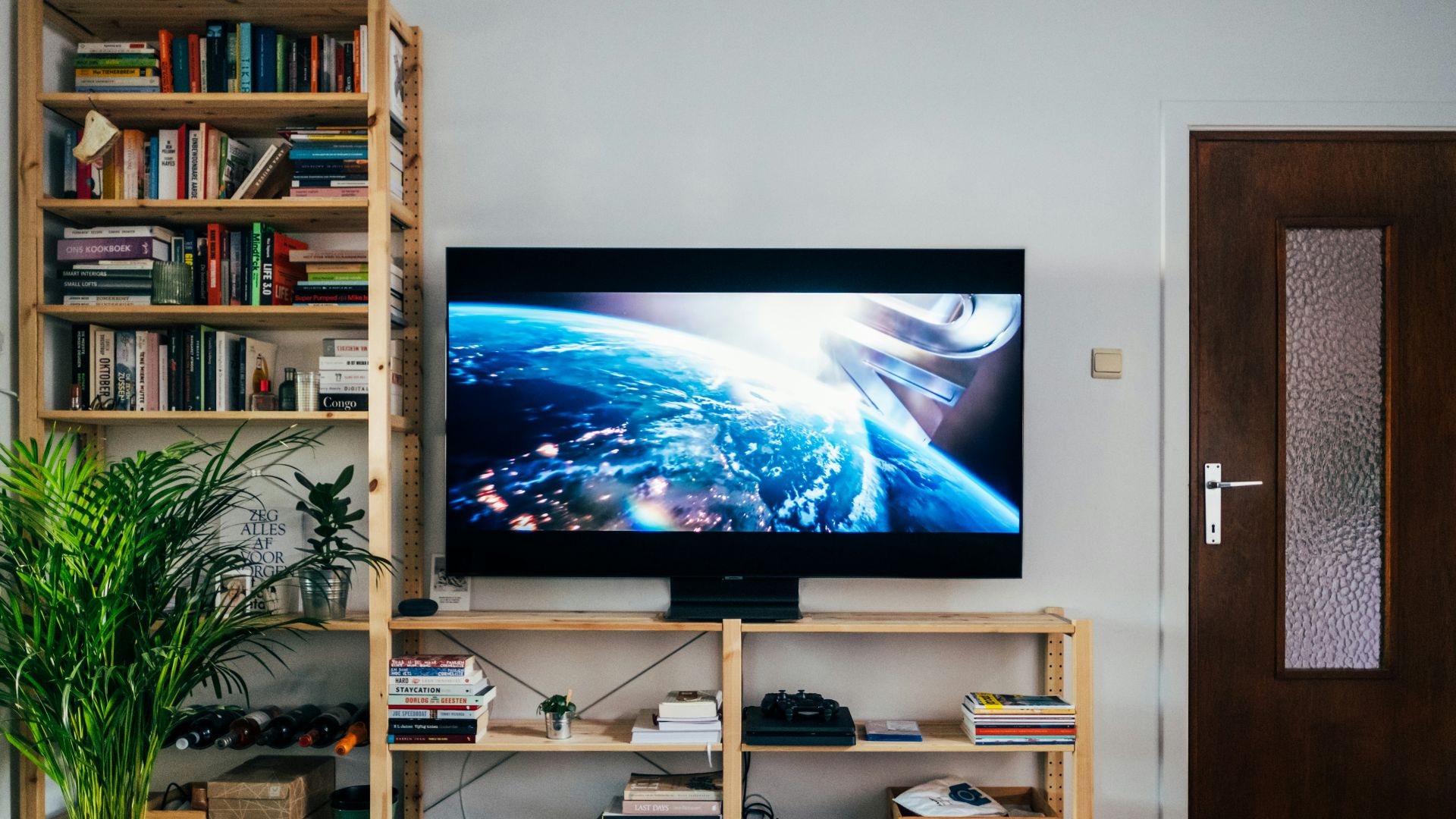 black flat screen tv turned on near brown wooden shelf