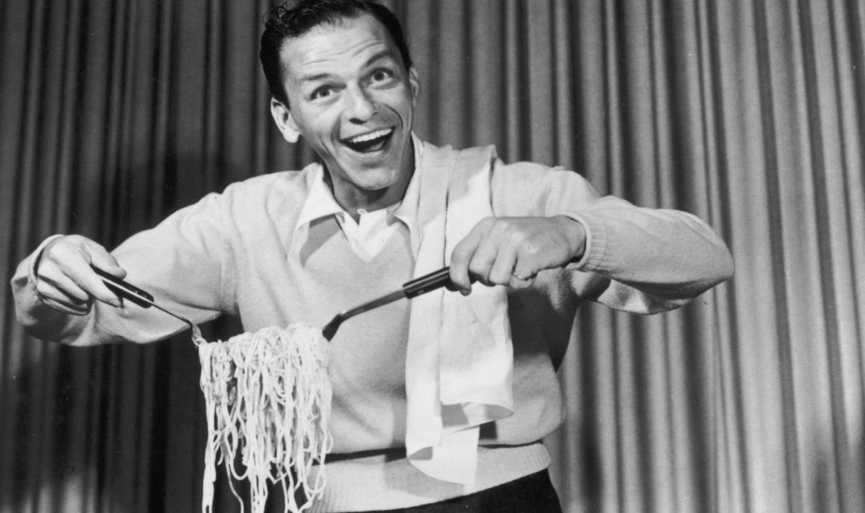 American actor and singer Frank Sinatra (1915 - 1998) clowning around with spaghetti for an EKCO products commercial on the set of CBS-TV's, 'The Frank Sinatra Show