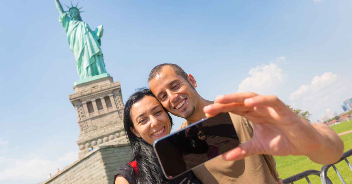 Couple Taking a Selfie with Statue of Liberty on Background