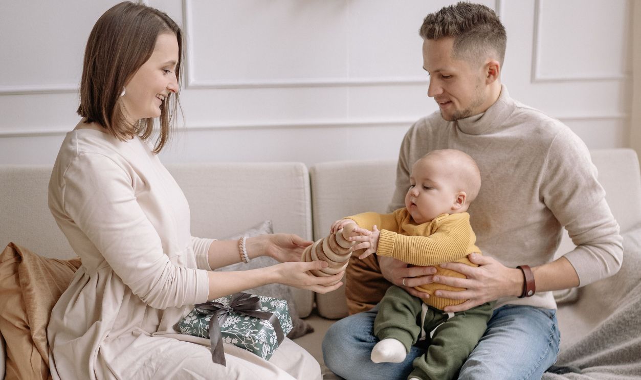 Family enjoying a festive moment with gifts and wreath indoors on a cozy winter day.
