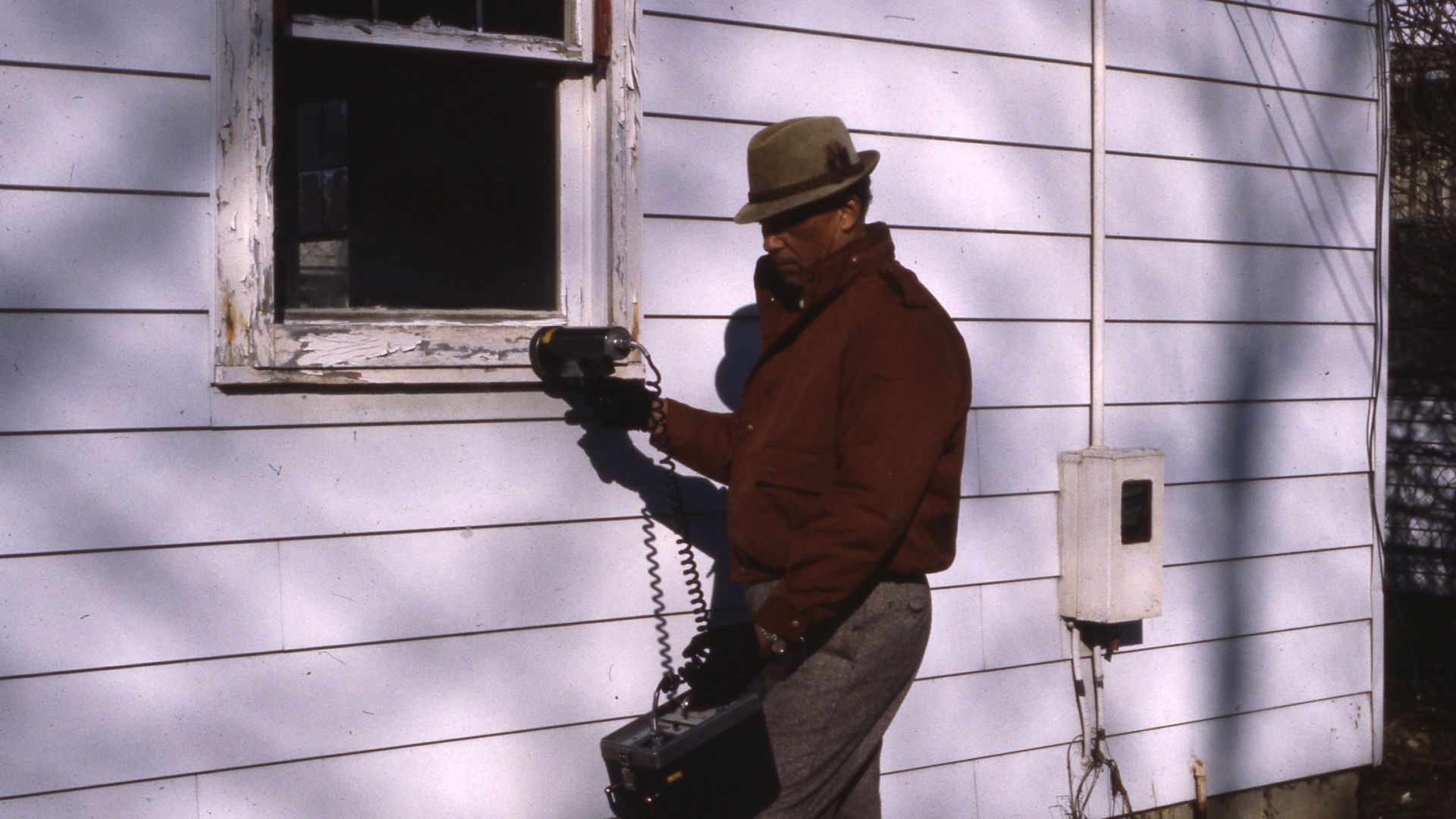 A man uses a lead paint detector to gauge the possible level of lead paint around an exterior home window.