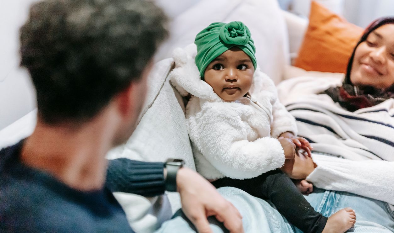 A joyful family with a baby girl relaxing together on a comfortable couch at home.