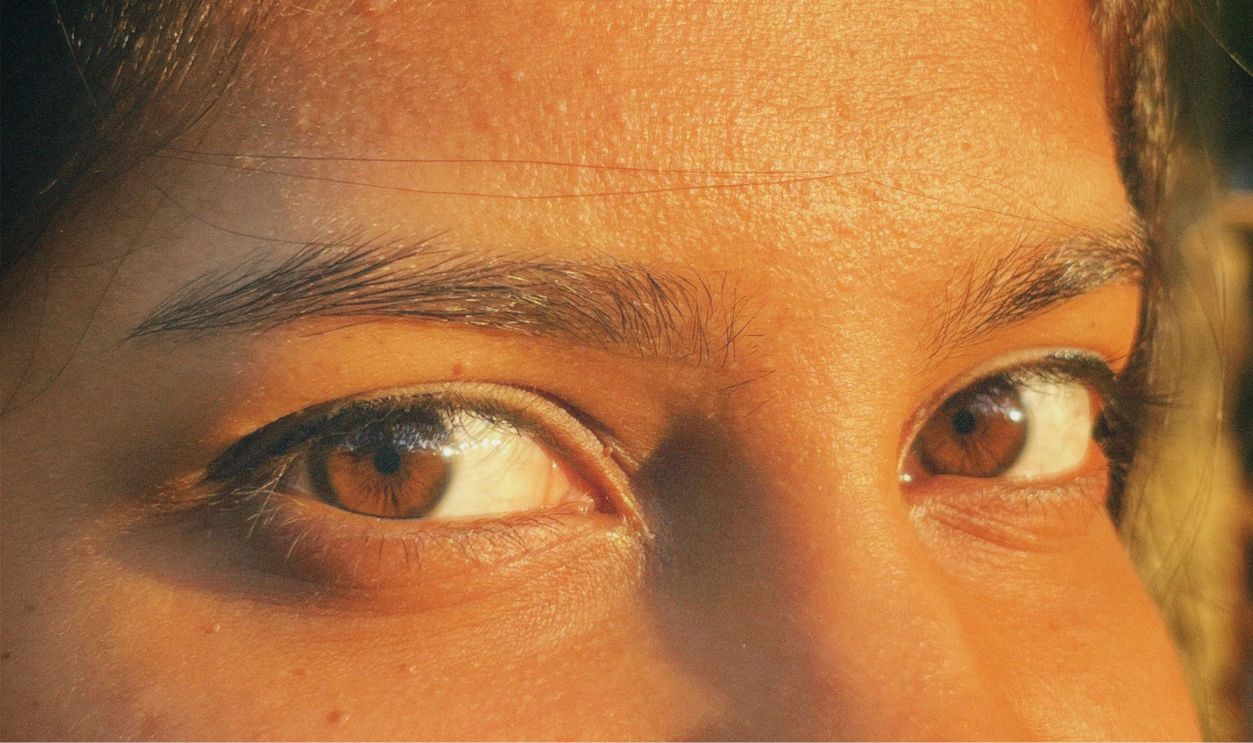 A close-up image highlighting expressive brown eyes with a warm sunlight glow.