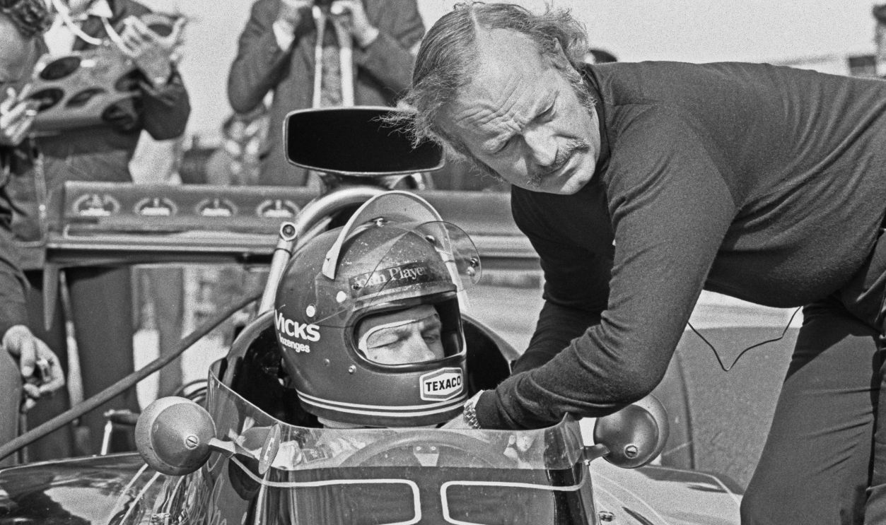 Swedish racing driver Ronnie Peterson (1944 - 1978) talking to British design engineer Colin Chapman (1928 - 1982, right) during the 1973 British Grand Prix at Silverstone, UK, 14th July 1973. Peterson is driving a Team Lotus Lotus 74 Ford. 