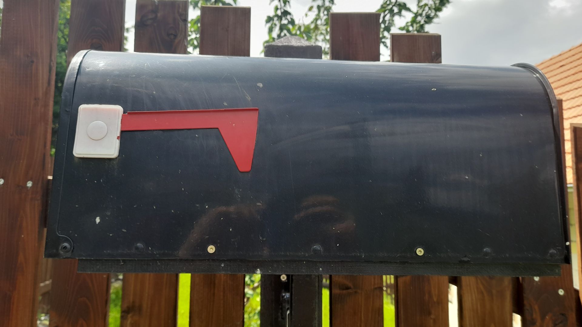 Black mailbox mounted on a fence