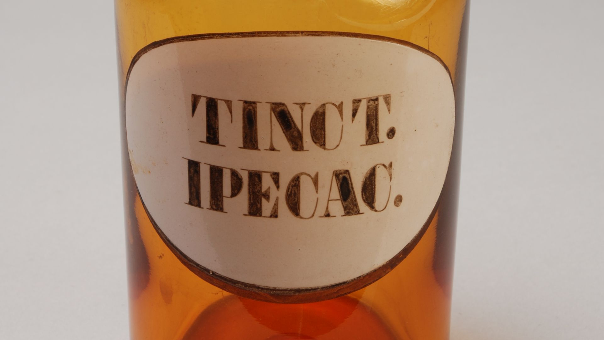 Objectgegevens Titel:  	Bruine stopfles met label: “TINCT. IPECAC.” Beschrijving:  	Bruine cilindrische fles met korte smalle geslepen hals. Achthoekige geslepen stop. Tinct. Ipecac. is een tinctuur van ipecacuanha oftewel Zuid-Amerikaanse braakwortel en 