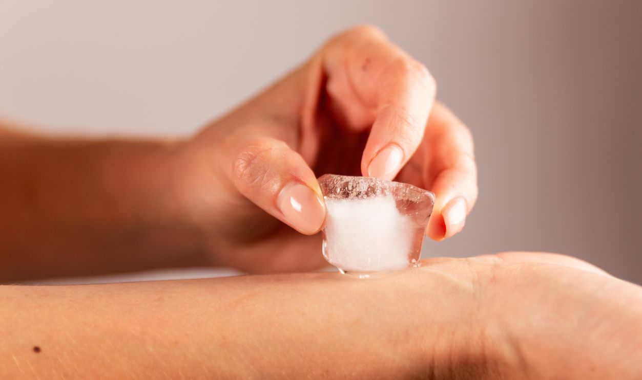 Shutterstock - 2345985185 - Woman rubbing ice cube on her wrist. Weird ice hack against obesity.