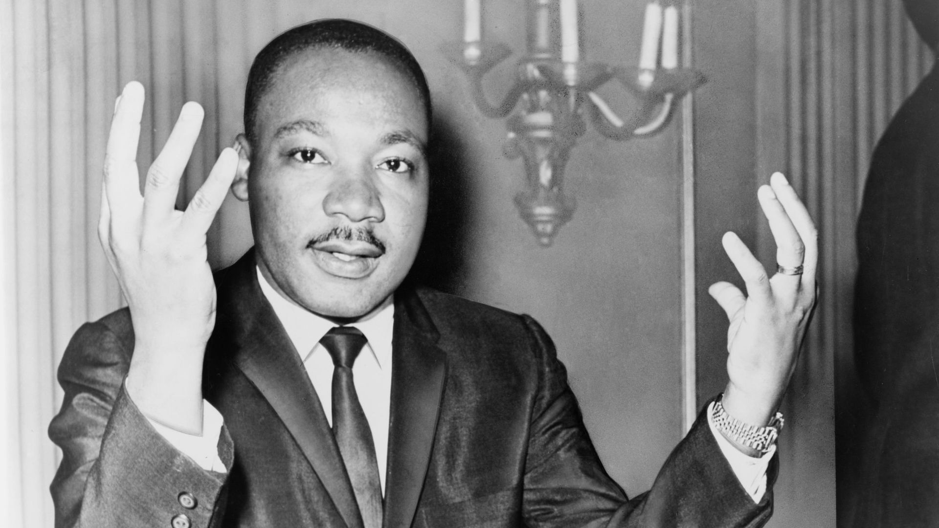 Rev. Martin Luther King, head-and-shoulders portrait, seated, facing front, hands extended upward, during a press conference / World Telegram & Sun photo by Dick DeMarsico.