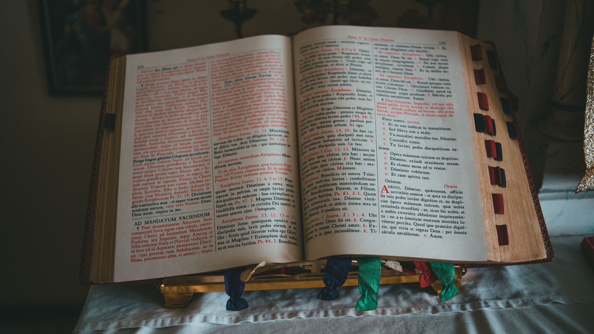 A Bible open on an altar with Latin text, featuring colored ribbons.