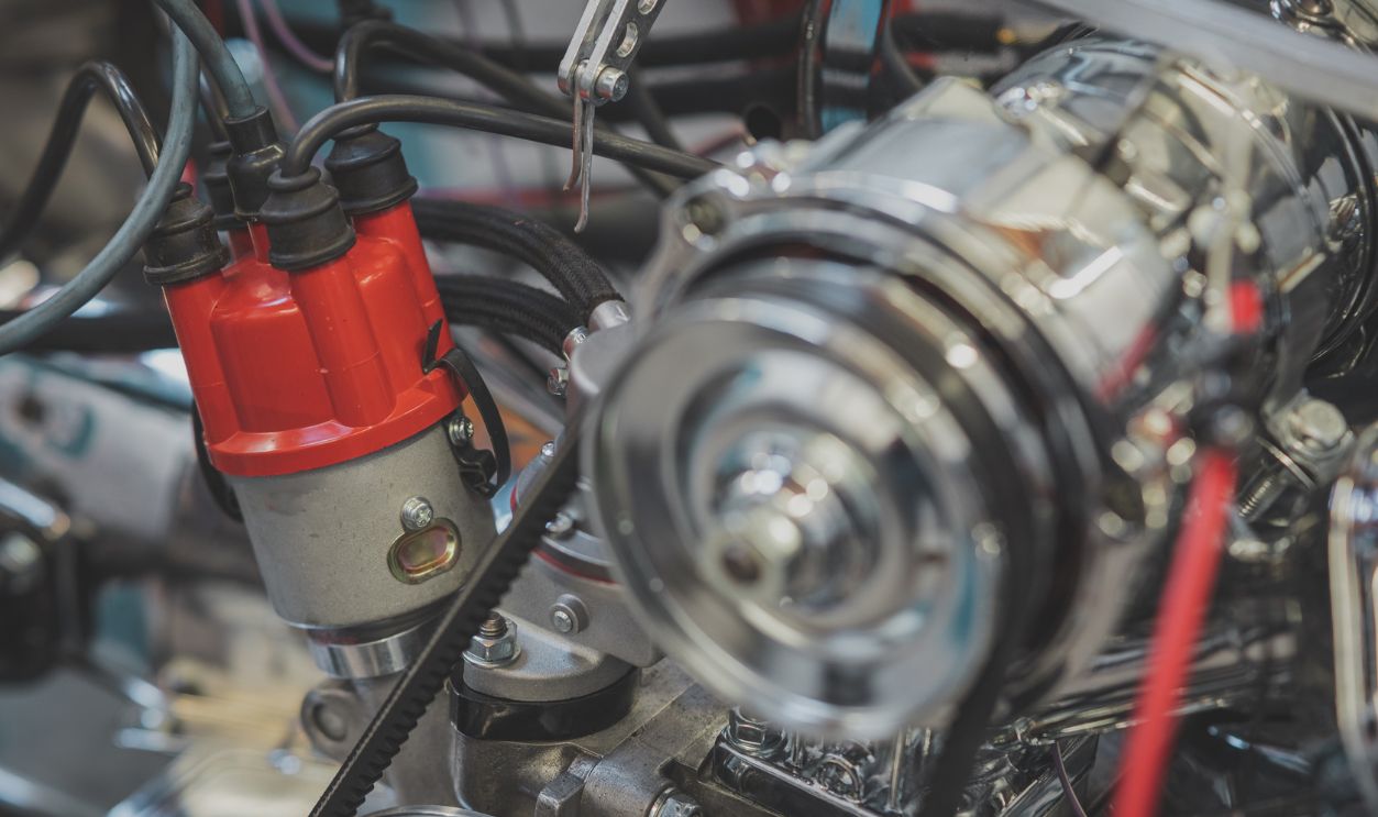 Shutterstock - 2270205183 - Distributor and distributor cap of a vintage car, visible ignition cables of a four cylinder engine of older type. Racing engine being built with emphasis on distributor.