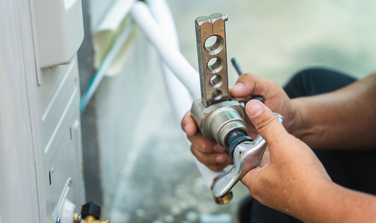 Shutterstock - 2761800689 - Air conditioning technician using manual flaring tool on copper pipe for installation, HVAC worker hands preparing copper tubing with professional flaring kit for refrigerant line connection.