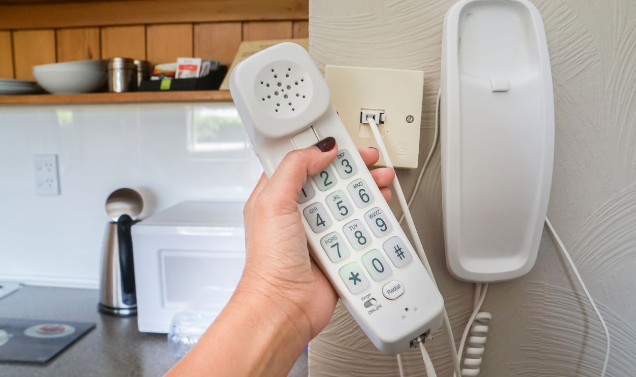 close up woman hold landline telephone at the house wall