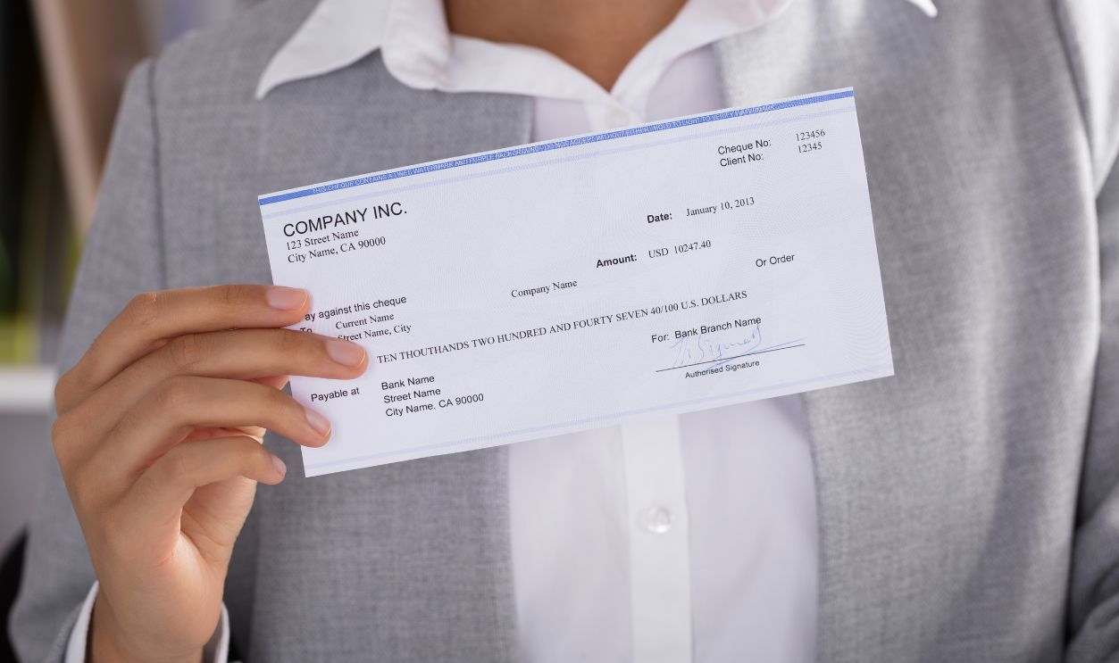 Midsection Of Businesswoman Showing Cheque At Office