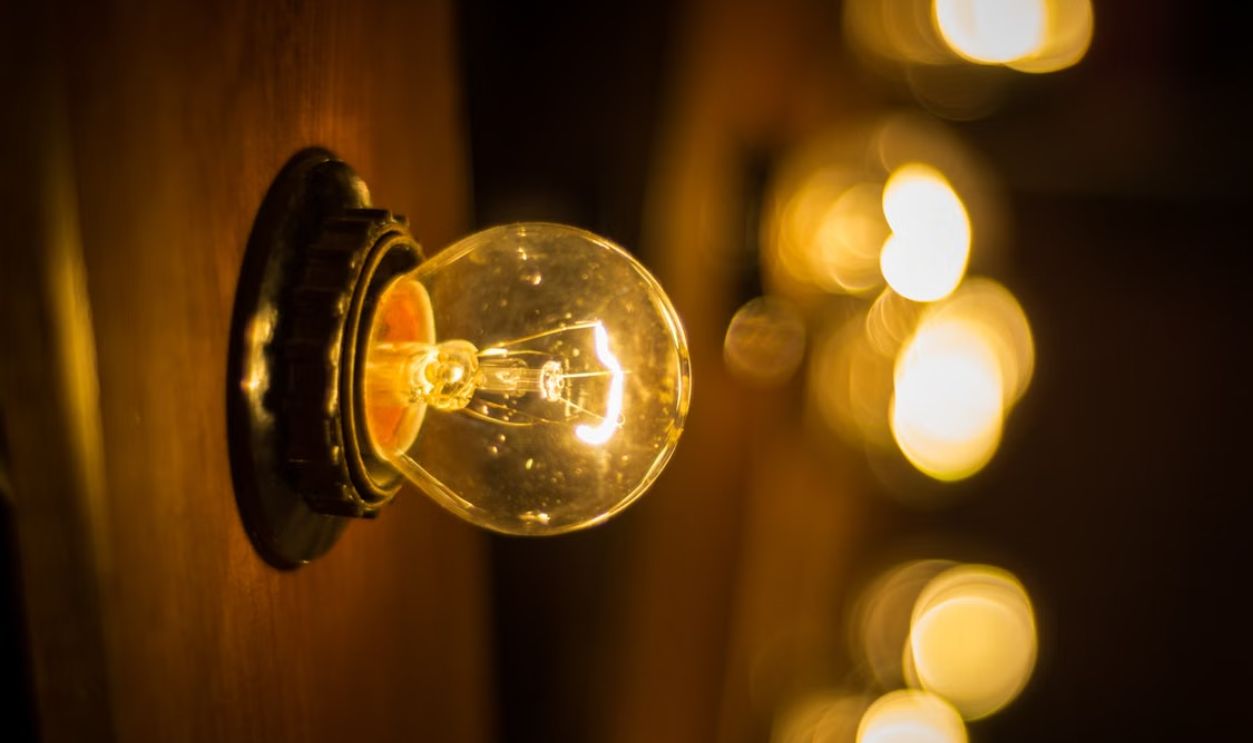 A close-up of a glowing light bulb with a warm, blurred background effect