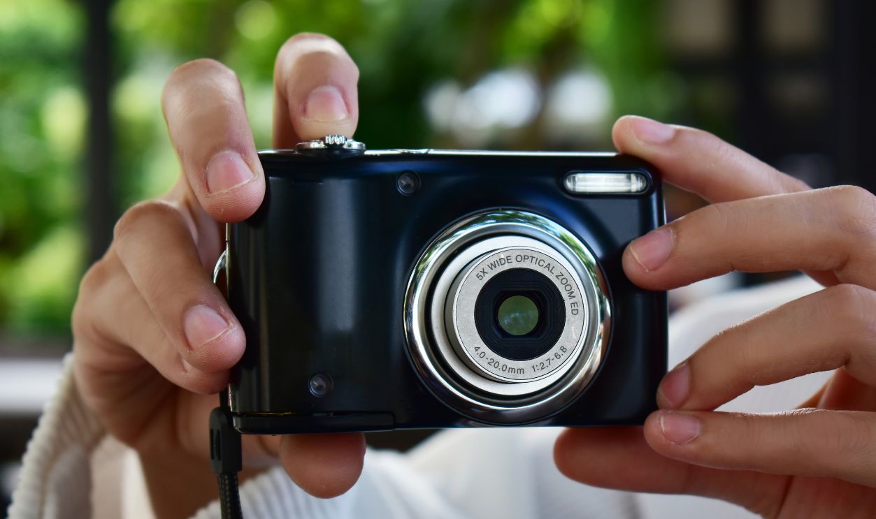 Compact digital camera Black in hand with open lens