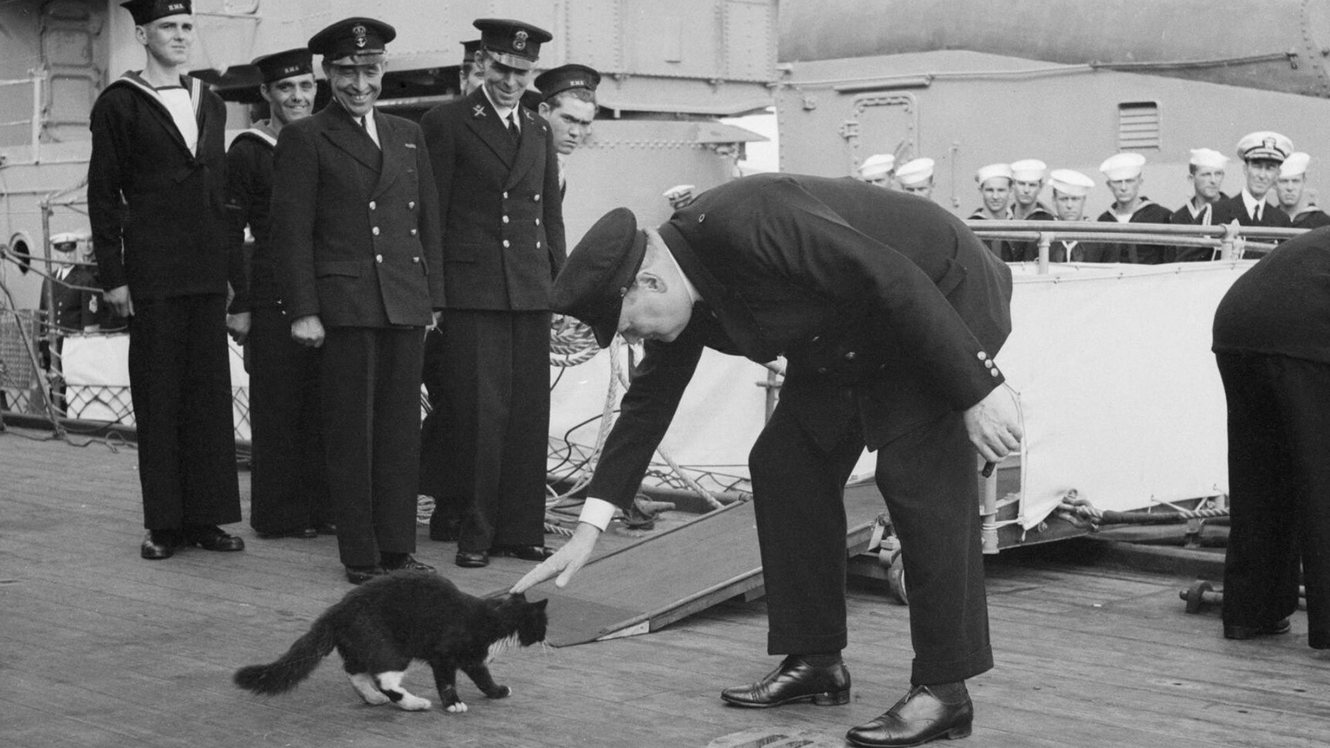 Atlantic Conference August 1941: Churchill restrains 'Blackie' the cat, the mascot of HMS Prince of Wales, from joining USS McDougal, an American destroyer, while the ship's company stand to attention during the playing of the National Anthem.