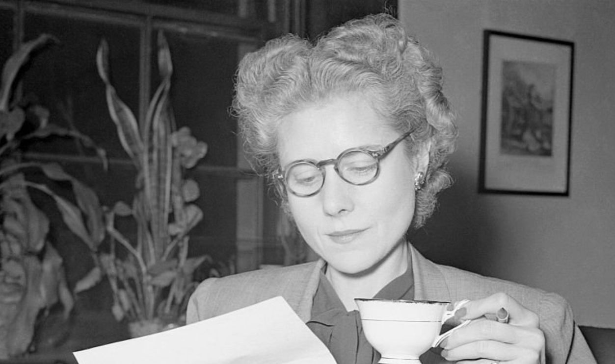 Representative Clare Boothe Luce drinks a cup of tea while reading a letter.