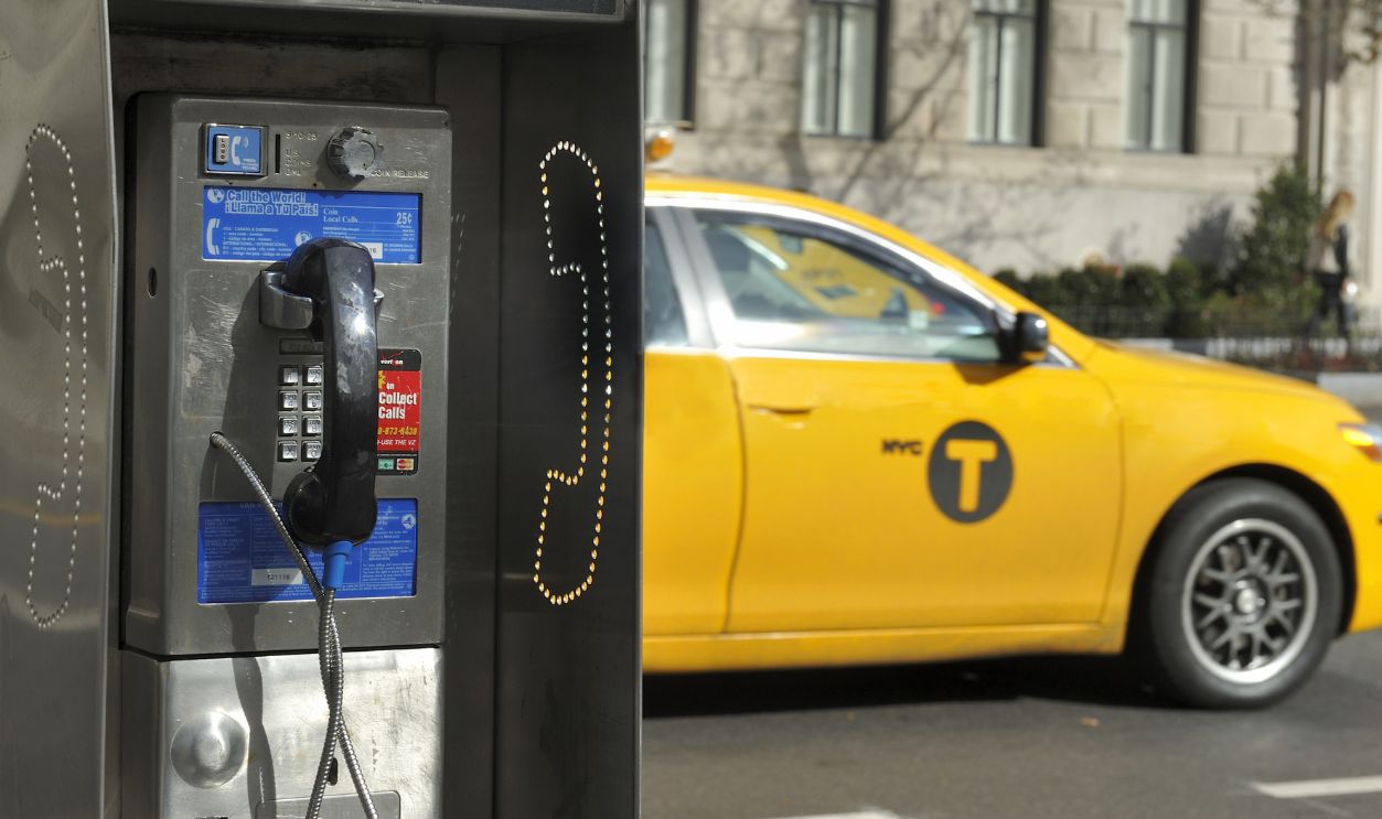 NEW YORK CITY, NEW YORK, USA - NOVEMBER 15, 2012: Old fashioned pay phone on a New York City street with a taxi passing by.November 15, 2012,New York