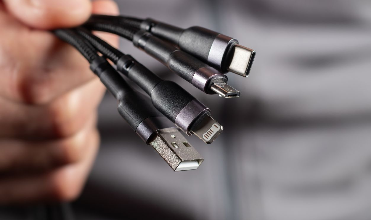 The hand holds a universal USB cable. USB Type C, Micro USB, Usb lightning.