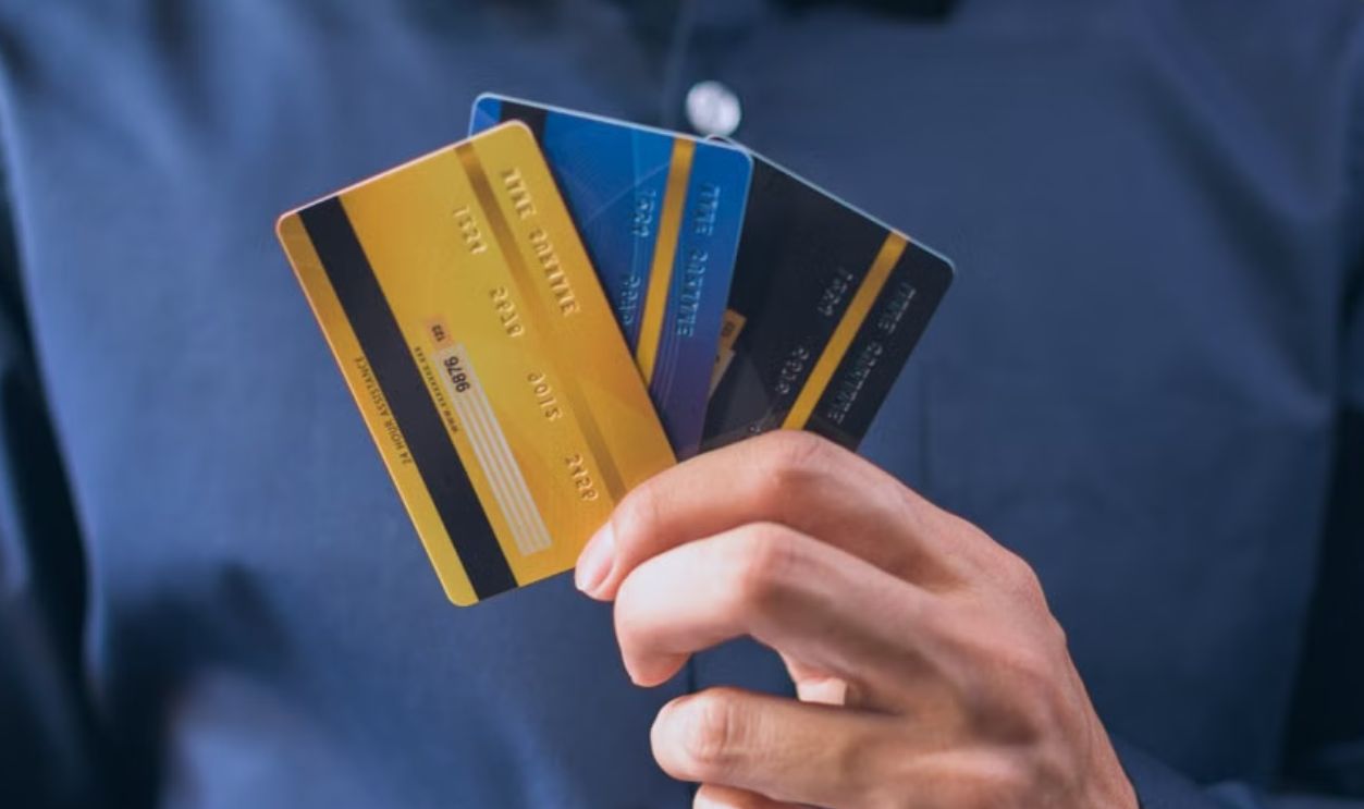Person holding three credit cards, symbolizing finance, security, and e-commerce