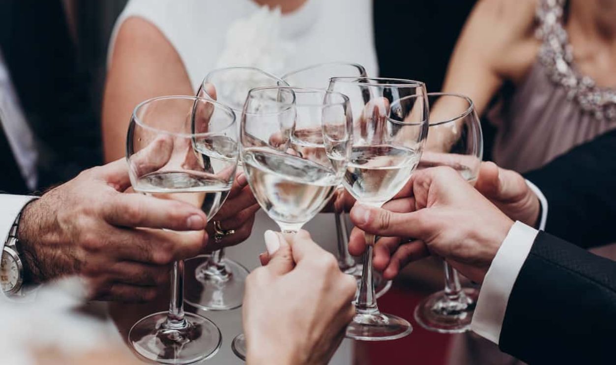 Shutterstock - 618266228 - Christmas celebration. people toasting with champagne and wine glasses in hands clinking at luxury wedding reception at restaurant.