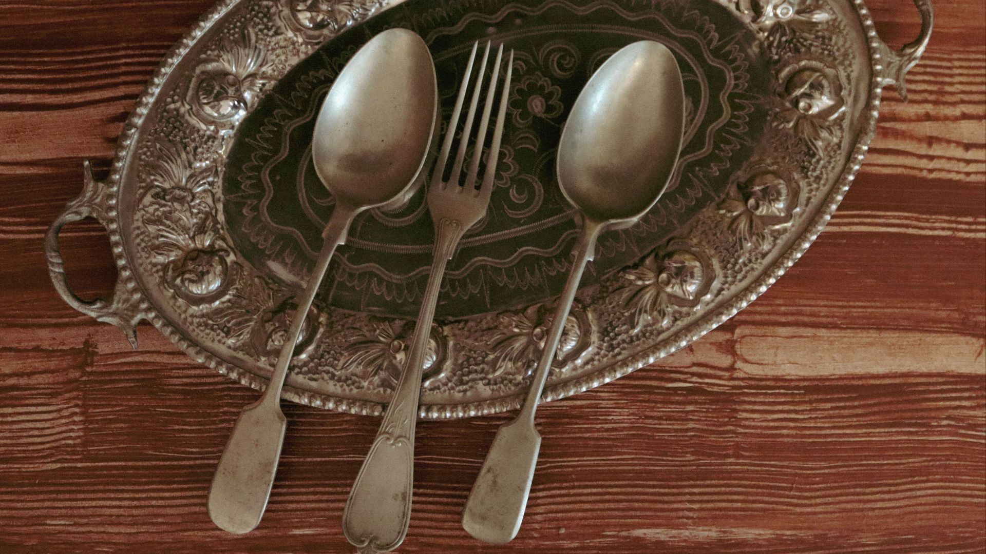 Top view of antique silverware on a decorative silver tray, perfect for vintage dining scenes.