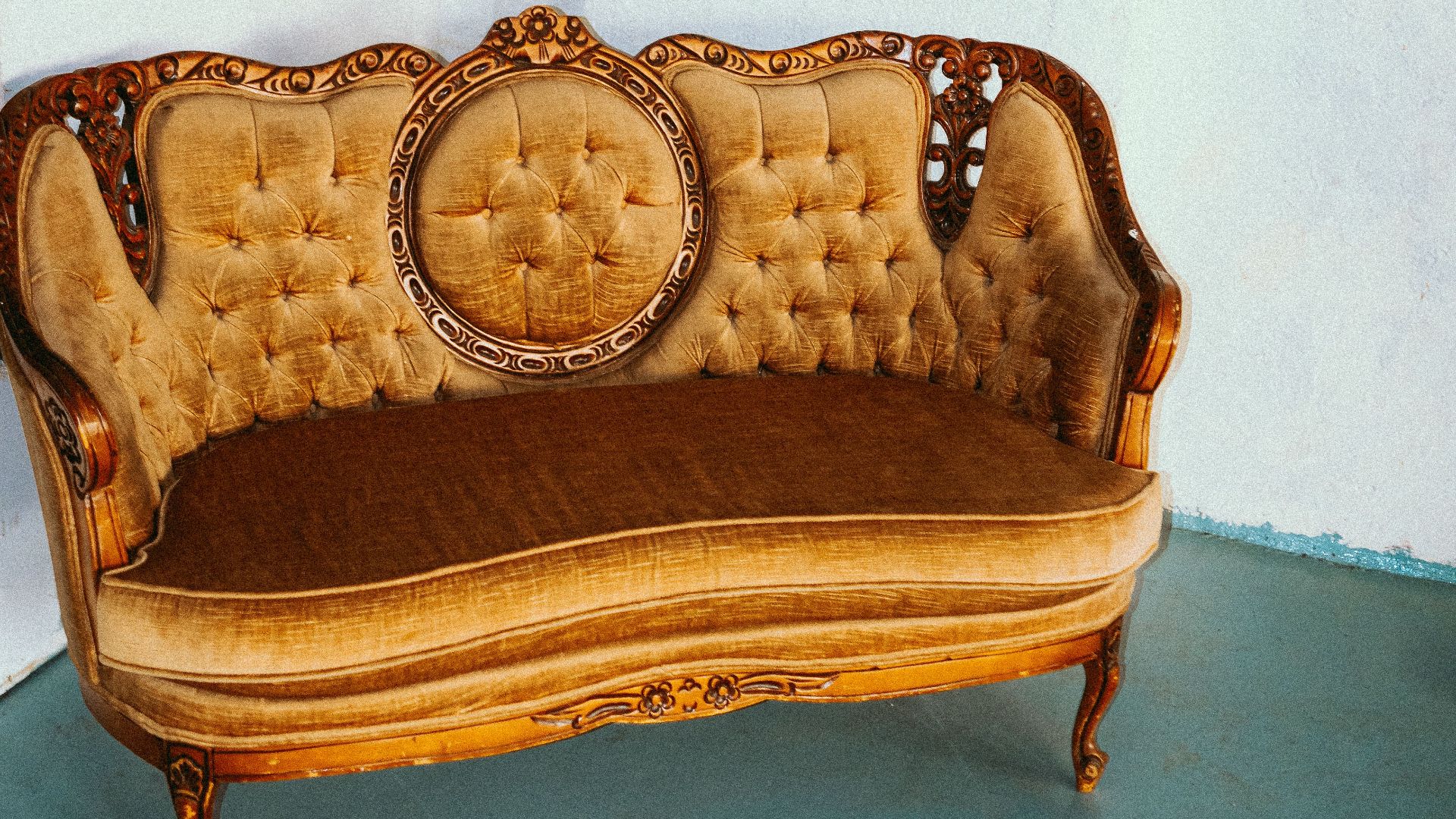 Ornate vintage Louis XIV style sofa against a minimalist wall.