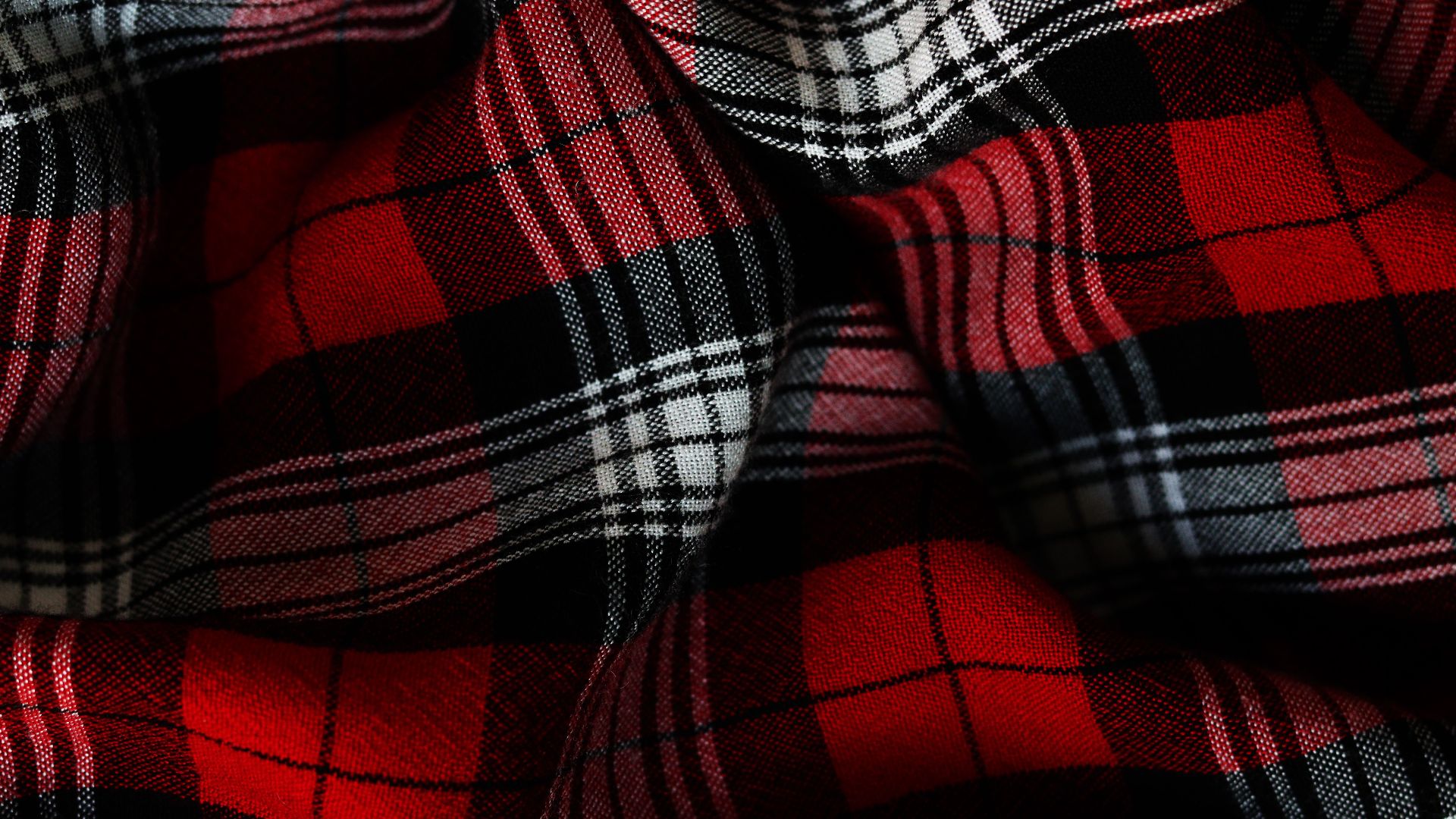 Detailed close-up of a vibrant red and black plaid fabric highlighting texture and pattern.