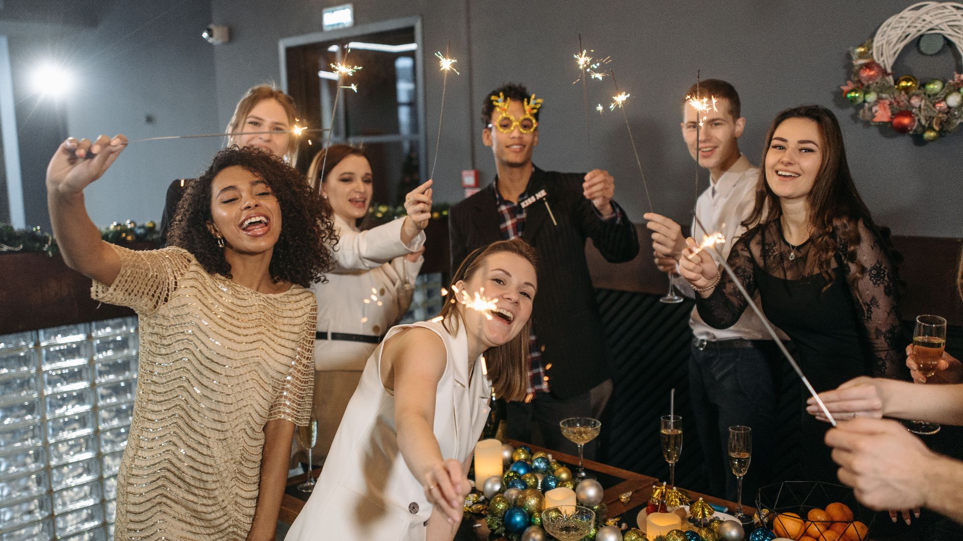 Group of diverse colleagues celebrating with sparklers at an office party.