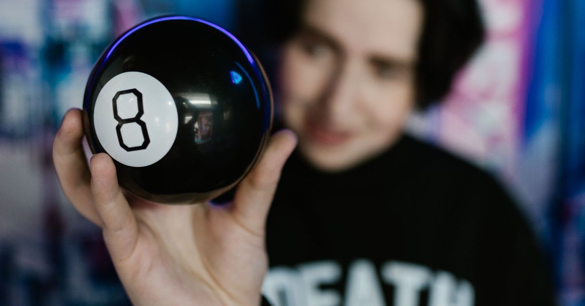 A person holding a magic 8 ball in a dimly lit room with a neon backdrop, creating a mysterious vibe.