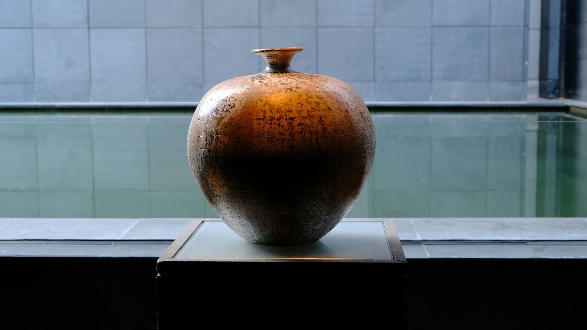 Large ceramic vase displayed by a tranquil pool