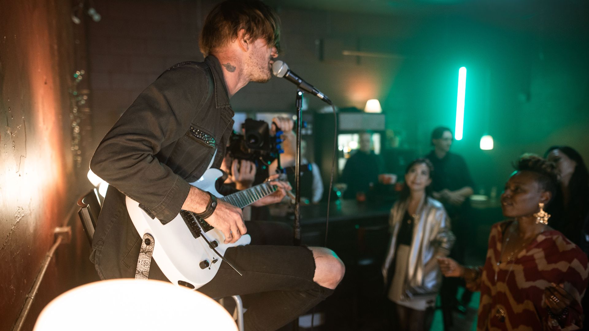 A dynamic live music performance featuring a guitarist and engaged audience in a cozy venue.