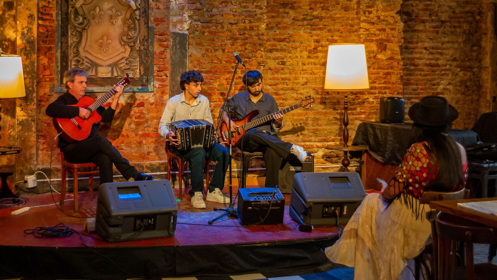 Three musicians performing live in a cozy Buenos Aires bar with guests enjoying the atmosphere.
