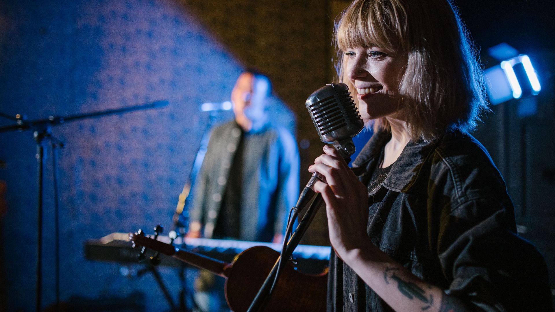 Smiling caucasian woman singing with vintage microphone during live music performance.
