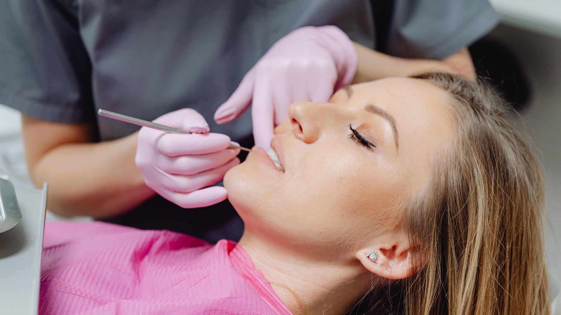 A female patient receives a dental examination by a dentist in a clinic.