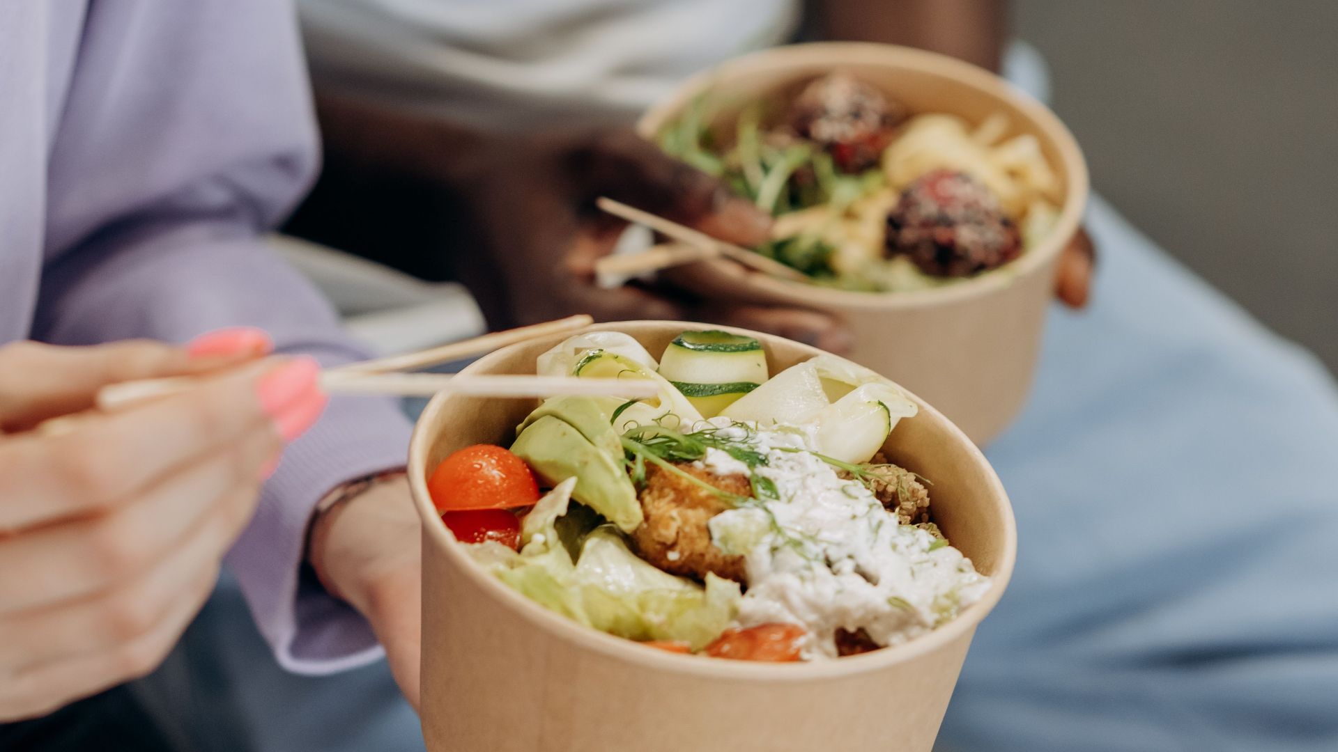 Two people enjoying nutritious salad bowls with fresh ingredients indoors.