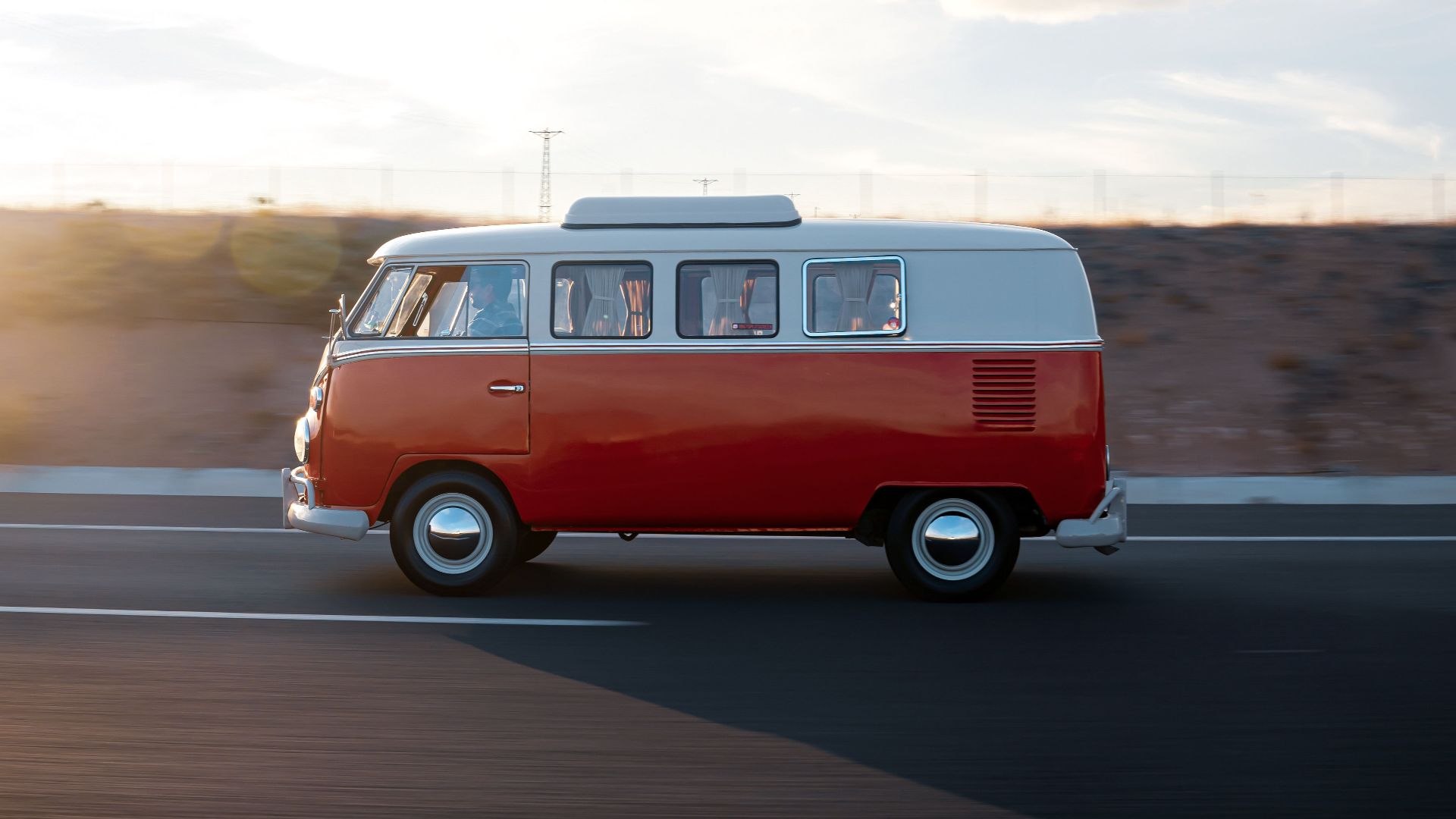 A classic Volkswagen van drives on a highway in Ankara, Türkiye during sunset.