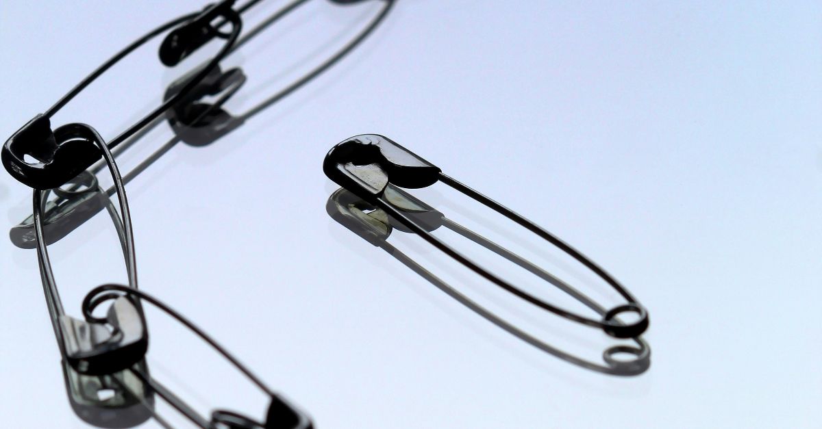 silver safety pin on white paper