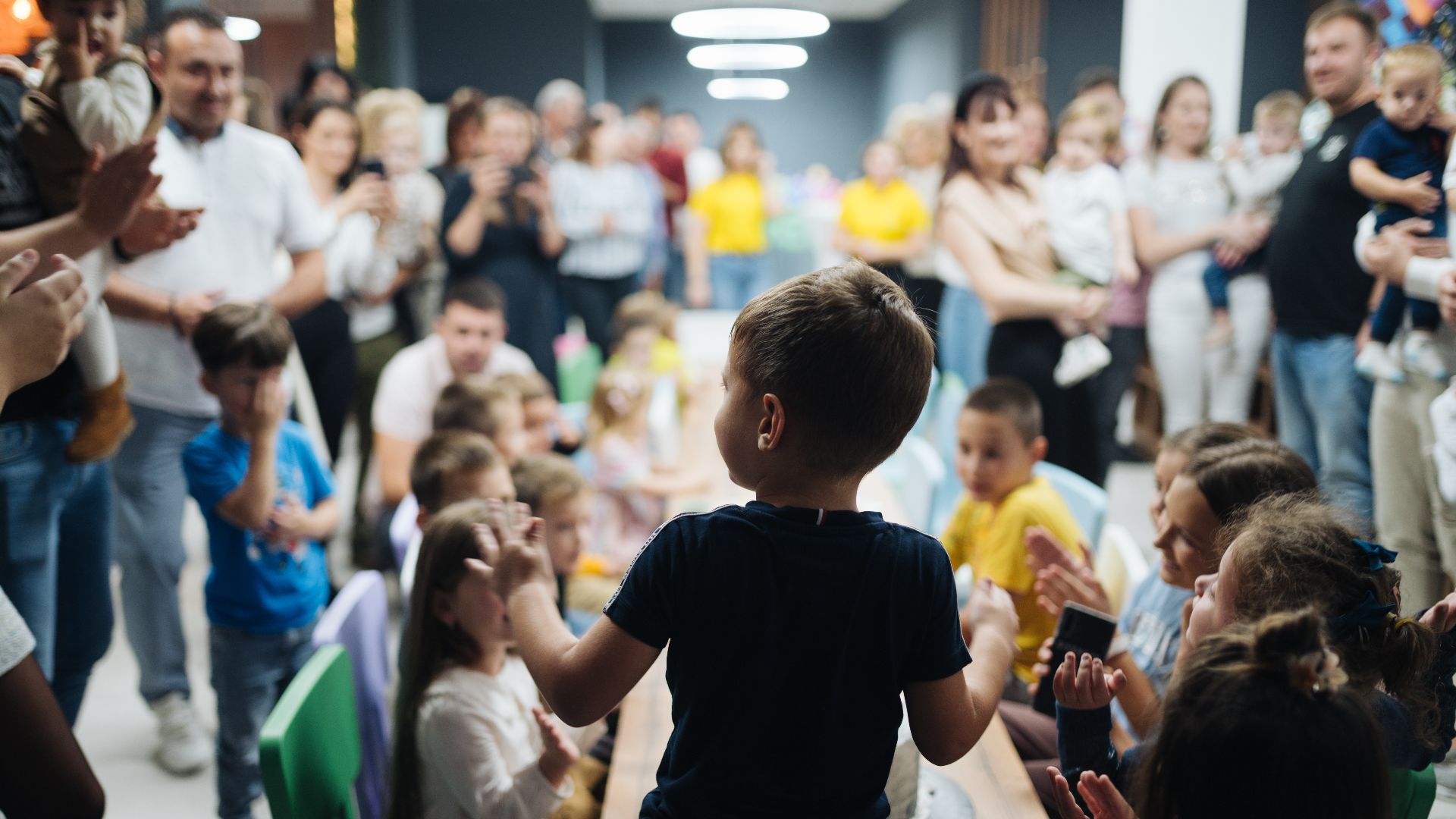 Back view of a kid blowing candles at birthday party