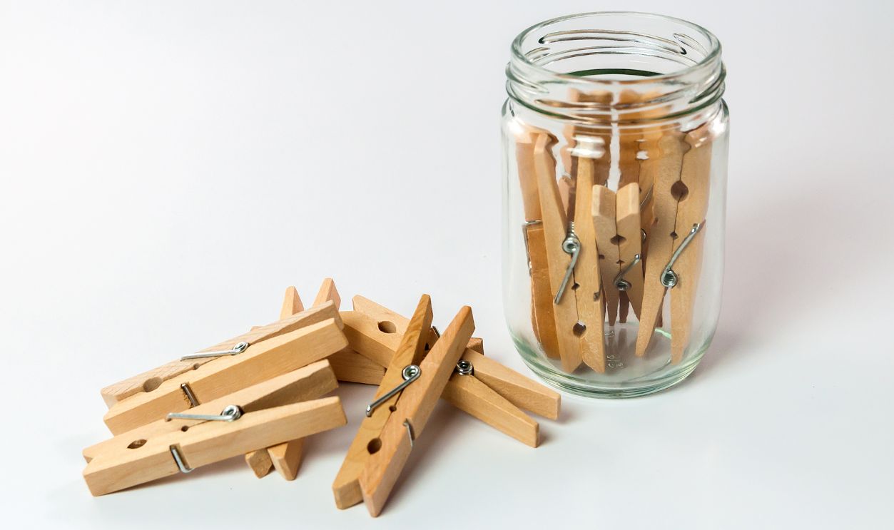 Shutterstock - 369550673 - Wooden cloth pegs, wooden cloth pegs in glass jar on white background.