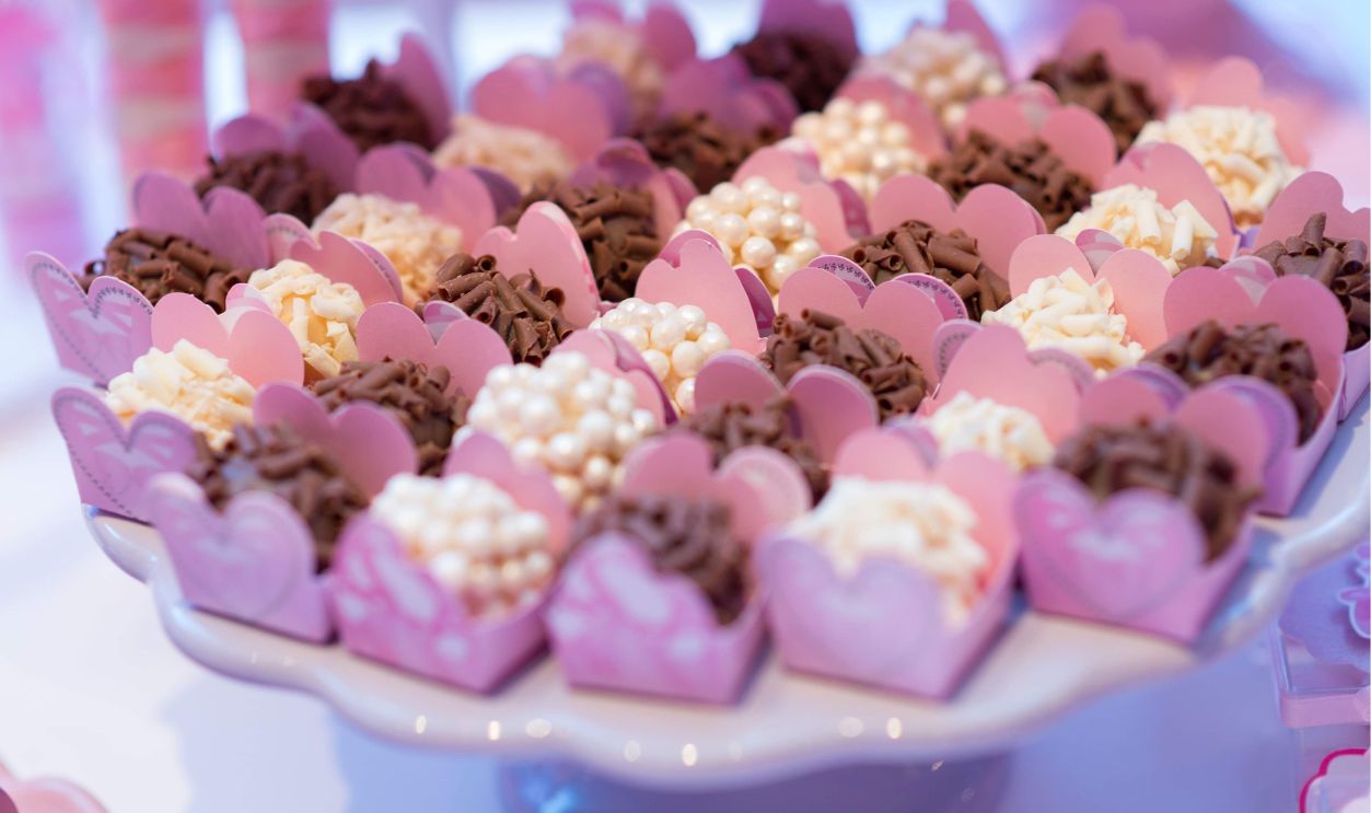 A delightful assortment of chocolates elegantly presented in pink heart-shaped holders, perfect for dessert lovers.
