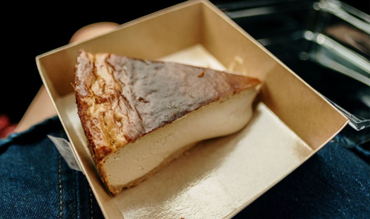 Close-up of a delicious cheesecake slice in a brown cardboard box, ready to enjoy.